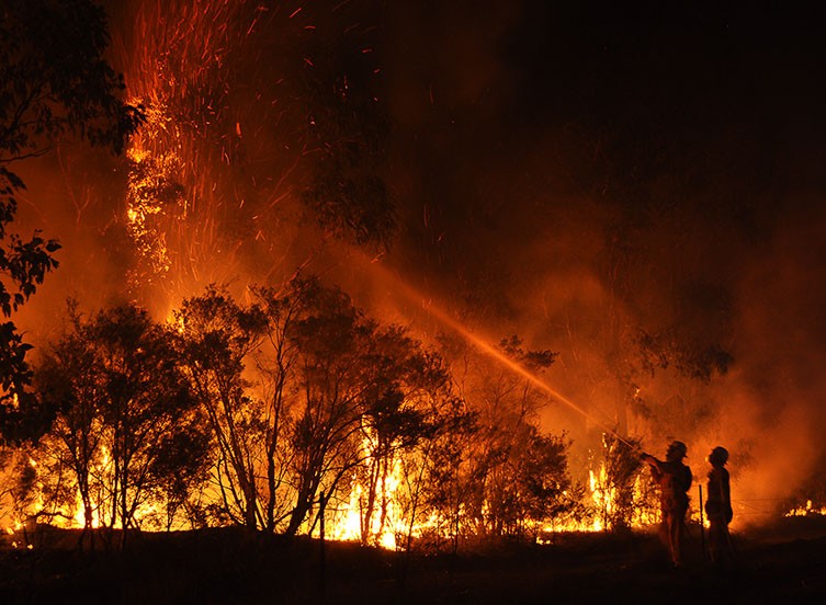 Two firefighters try to control a bush fire in New South Wales, Australia