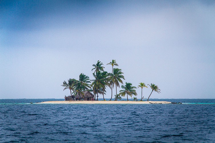One of the San Blas Islands. It is covered by several palm trees and a small wooden house. 